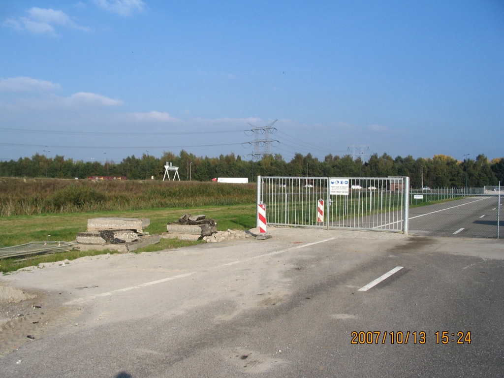 IMG_0631.JPG - Westelijke toegangspoort tot het directieketencomplex, waaronder een verkeersdrempel is aangelegd van klinkers. Hiertoe is een strook asfalt uit het v/h A58 wegdek gefreesd, de resten waarvan we links zien liggen.