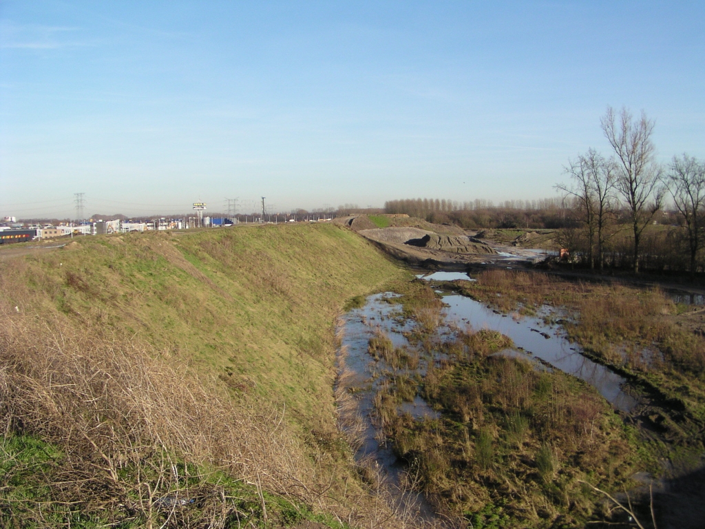 p2080031.jpg - Aan de achterzijde van de forse geluidswal tussen de A58 en Eindhoven Noord is een rommelig landschap van zandhopen en modder.