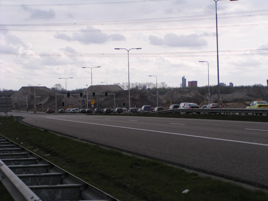 p4130025.jpg - Toch moet het een hoopgevend gezicht zijn voor de automobilist die zojuist van 120 km/uur is afgedaald naar nul voor de VRI, die imposante grondwerken vermengd met de Eindhovense skyline.