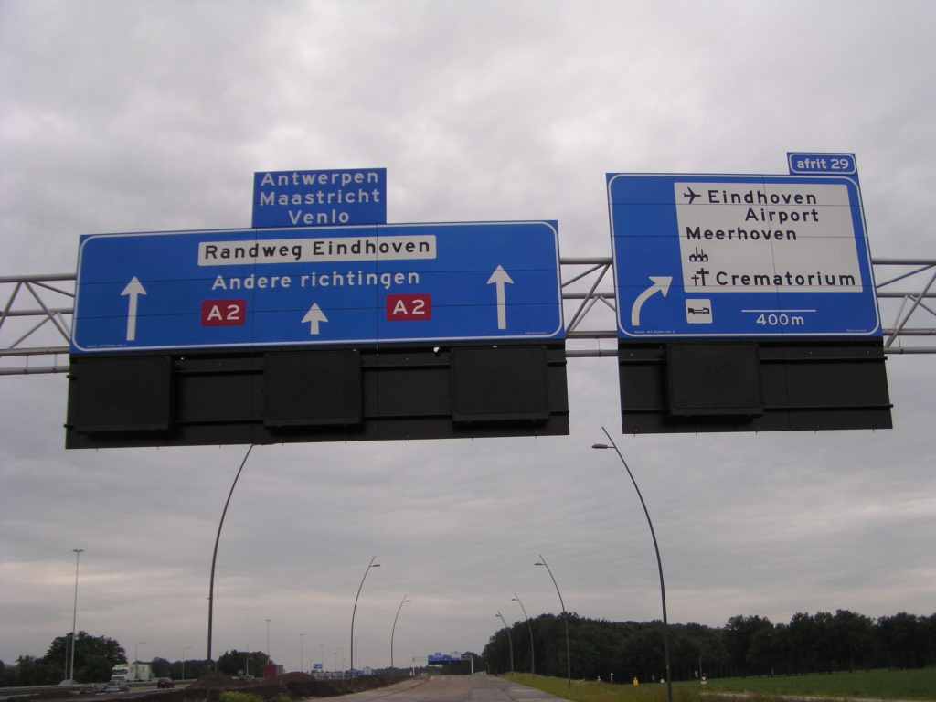 p6140114.jpg - "Andere richtingen", dat moet toch wel uniek zijn op een (semi-) autosnelweg. De ruitertjes met de doelen Antwerpen, Maastricht en Venlo zullen ongetwijfeld verdwijnen als de parallelbaan zijn uiteindelijke functie heeft gekregen. Verder vallen natuurlijk de omhoog wijzende pijlen op, conform de  Nieuwe Bewegwijzering Autosnelwegen . Het nieuwe afritsymbool ontbreekt echter. Ook zouden de witte doelen op een apart servicebord moeten staan. De afgeplakte bedrijventerreinnummering op het rechter bord kwamen we ook al tegen op het  allereerste nieuwe bord op de parallelbaan oost , maar hier is het industriesymbooltje zelf niet afgeplakt. Tenslotte een opmerkelijk A2 wegnummerschildje, zonder witte bies, maar daar gaan we zo even wat beter naar kijken...