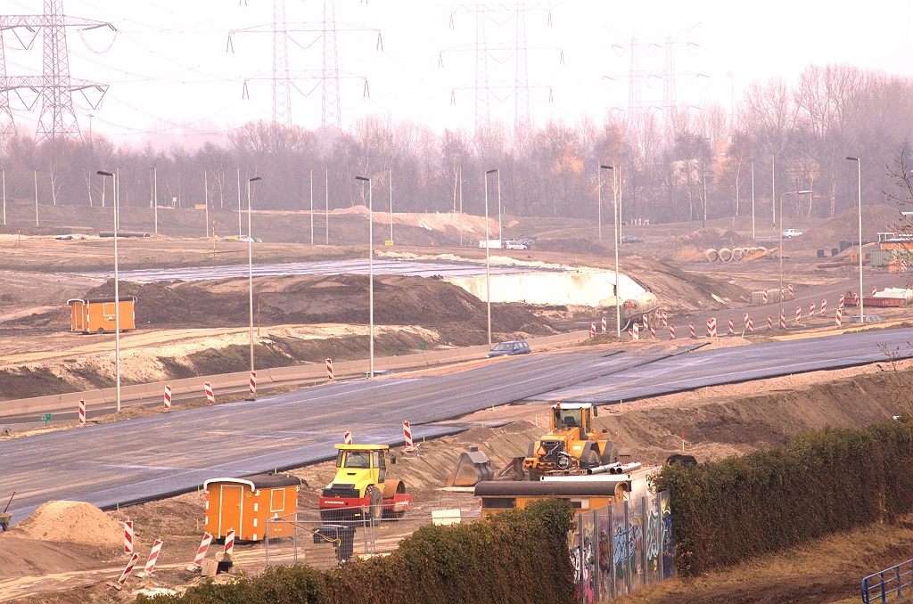 20090228-154123.jpg - Meer asfalt op de zuidelijke A50 rijbaan vanaf KW 45 in de richting Nijmegen. Het begin van de bocht naar het bodemaslichaam verderop (met de witte afdekking aan de voorzijde) is al aangelegd, tot aan het punt waar de huidige A58 nog in de weg ligt. Ten behoeve van de aanstaande faseringen zien we rechts een tijdelijke rijbaan "aangeplakt" die naar het oude A50/A58 kruispunt leidt.