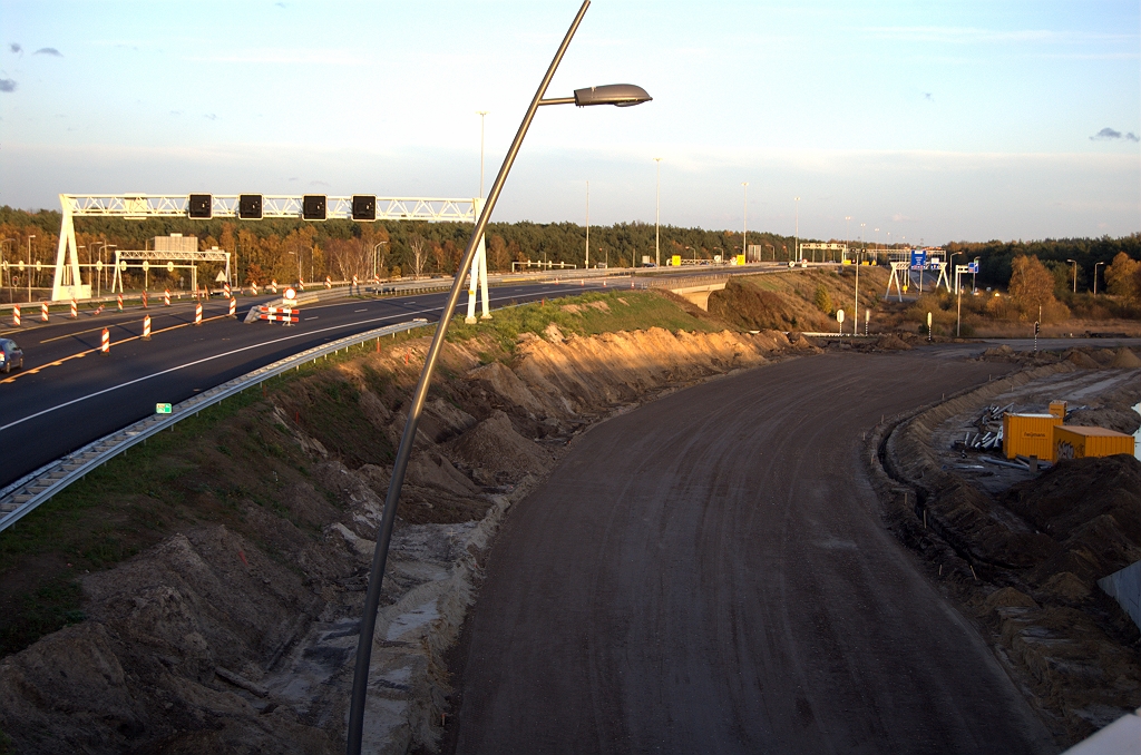 20091114-171823.bmp - Situatie kp. Leenderheide, met de A67 in de richting Venlo nog steeds verlegd over de andere rijbaan ten behoeve van het groot onderhoud aan de viaducten. Puinfundering aangebracht voor de definitieve ligging van het einde van de parallelrijbaan op de rotonde. De brede rijbaan die hier zo te zien moet komen herkennen we niet terug in zowel de trace- als de geoserviceskaart, die slechts twee rijstroken intekenen tot aan de rotonde. Het portaal waar de verkeerslichten aan hingen is te smal voor deze configuratie en is dan ook verwijderd.  week 200945 