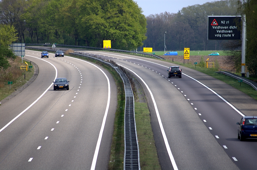 20100425-144944.bmp - Tweede van vier weekendafsluitingen wegens het aanbrengen van dubbellaags ZOAB op de N2 parallelrijbanen. Thans is het wegvak tussen de aansluitingen high tech campus en Veldhoven aan de beurt. Vandaar deze begroeting op een grafisch route-informatie paneel langs de A67 vanuit de richting Antwerpen. De omleidingsroute "V", die niet alleen voor het doel Veldhoven geldt, verloopt via het onderliggend wegennet in de Eindhovense kom.