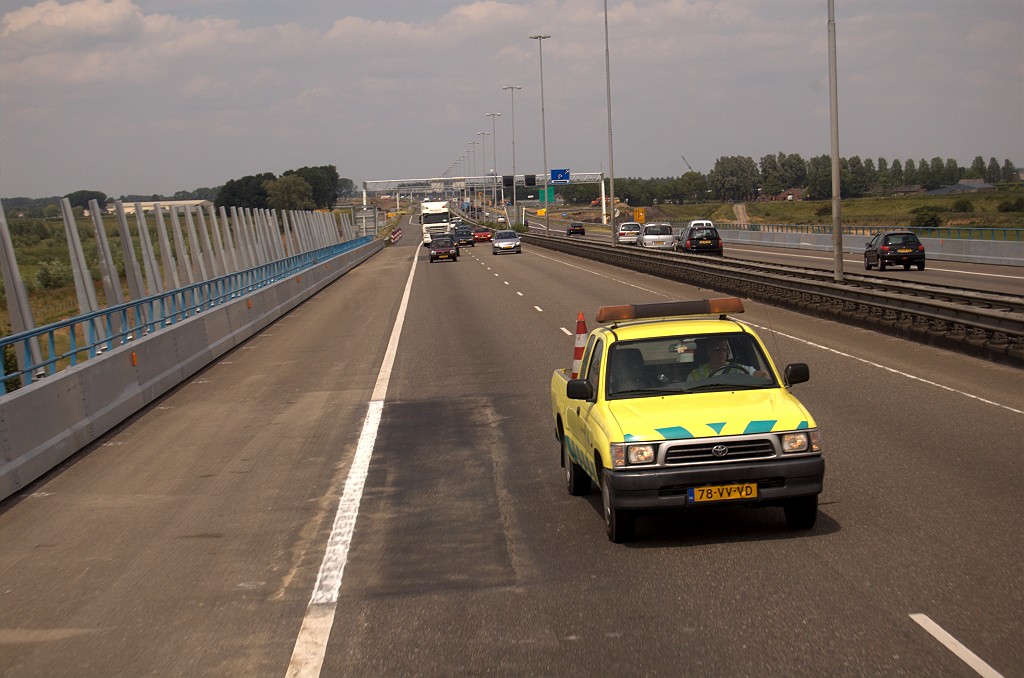 20090606-132650.bmp - Na het keren in de aansluiting Kerkdriel zijn we terug op de Maasbrug. Het RWS voertuig haalt ons niet in, maar neemt positie in om de touringcar veilig over de linkerrijstrook naar een werkverkeerafrit te derigeren. De strook vervangen asfalt wijst misschien op verstevigingswerken die zijn aangebracht in de brug voor de herinrichting van de rijbaan naar 3 rijstroken.